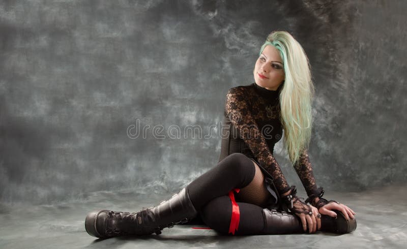 Young, seductive and provocative woman dressed in gothic style posing on the floor at studio. Young, seductive and provocative woman dressed in gothic style posing on the floor at studio