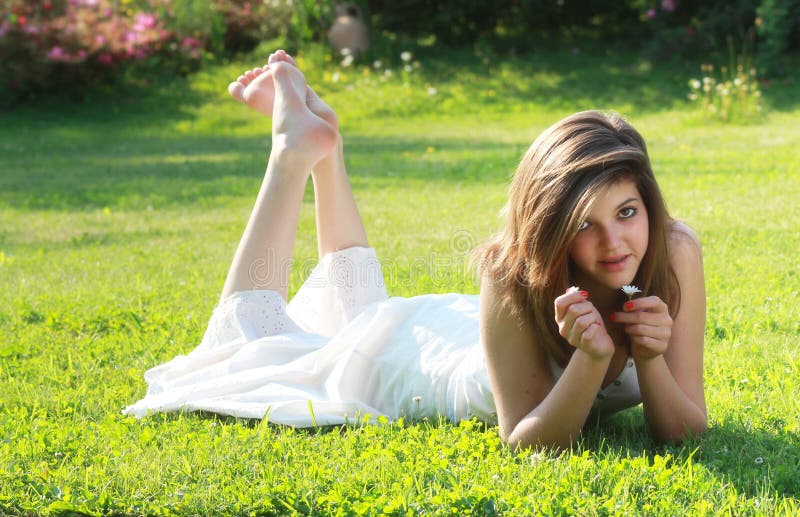 Pretty young girl lying on grass with bare feet