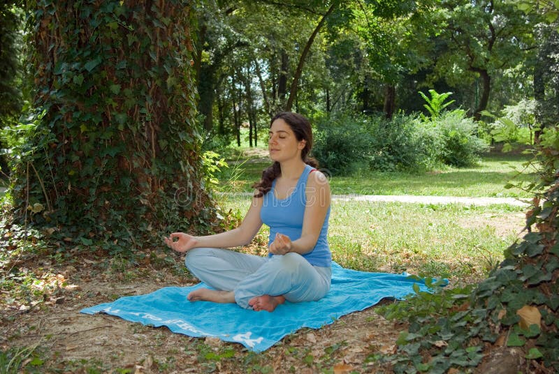 Pretty young girl meditating outside on grass