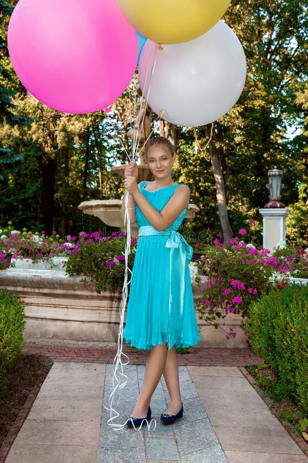 Pretty young girl with big colorful balloons walking in the park near the town - image royalty free stock photo Pretty young girl with big colorful balloons walking in the park near the town - image royalty free stock photo