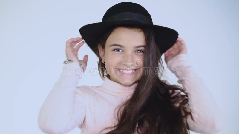 Pretty young lady in hat cheerfully poses at camera.