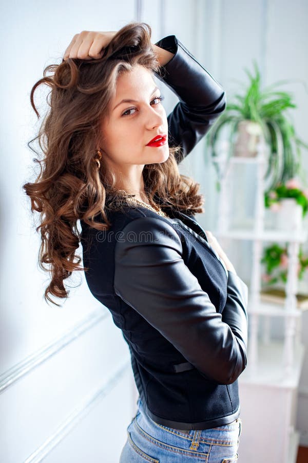 Young sensual woman posing on white wall. She dressed in black jacket royalty free stock image