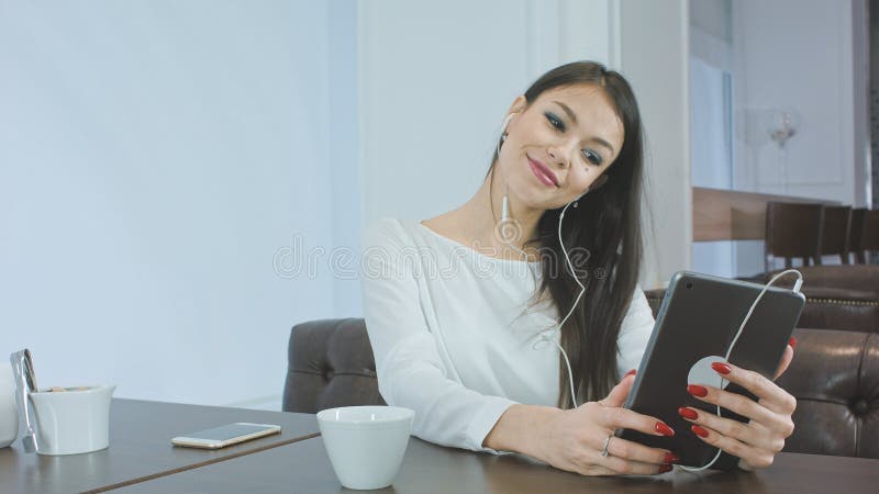 Pretty young woman checking her make up using tablet and preparing for video call