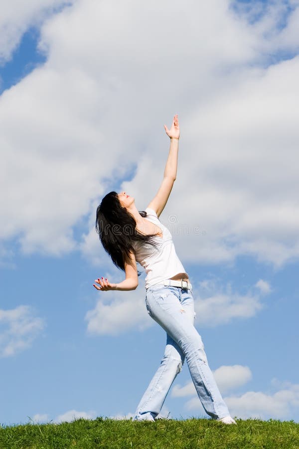 Pretty young woman dance on grass