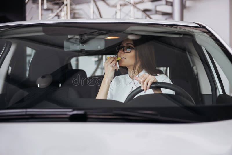 Pretty young woman driving new car.