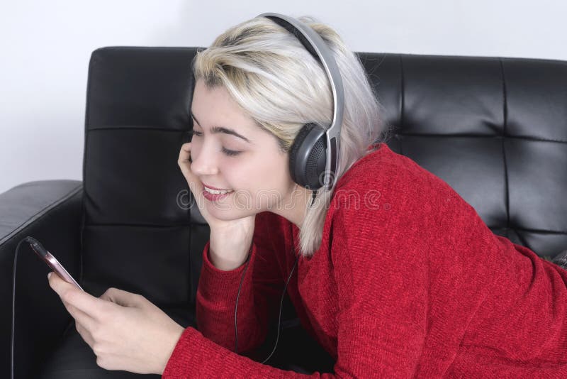 Pretty Young Woman Lying On The Couch And Texting With Her Smartphone 