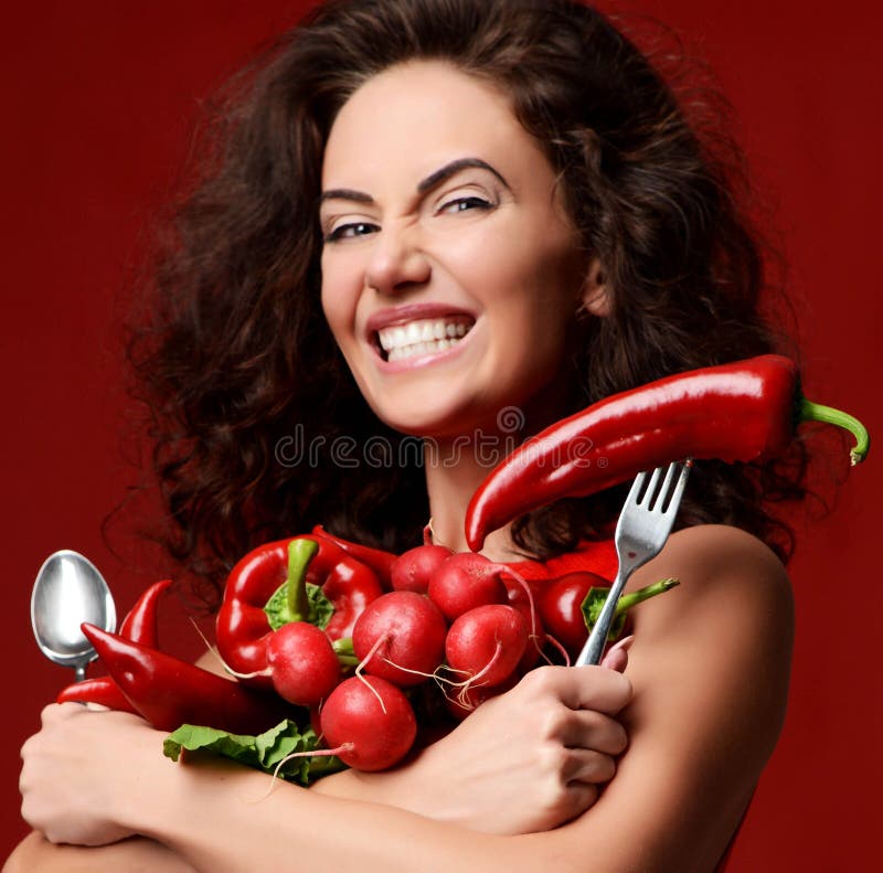 Pretty young woman posing with fresh red vegetables radish chili pepper green leaves lettuce parsley smiling