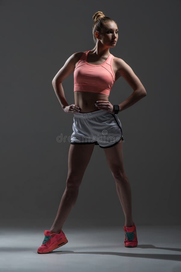 Full length portrait of cheerful female athlete showing her fit trained body. She is standing with arms akimbo. The girl is looking aide with confidence. Isolated. Full length portrait of cheerful female athlete showing her fit trained body. She is standing with arms akimbo. The girl is looking aide with confidence. Isolated