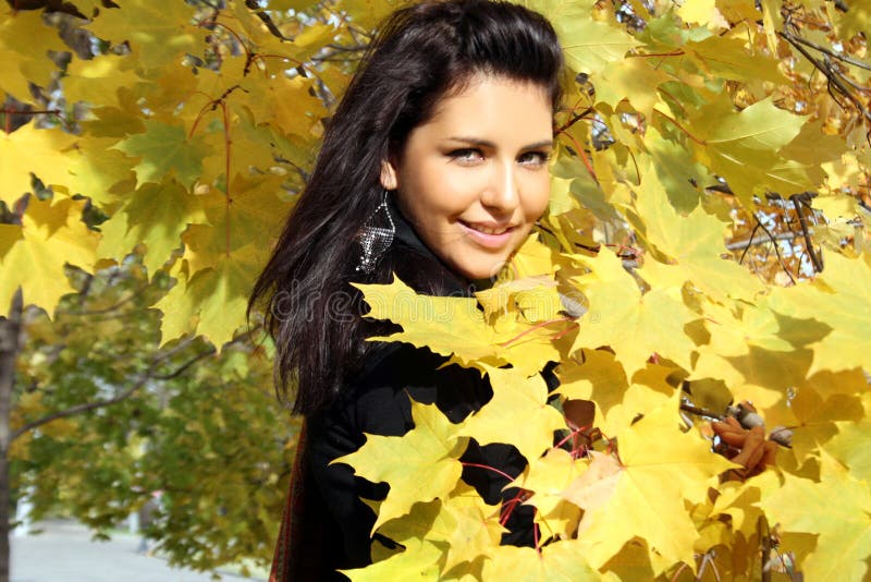 Pretty young woman standing near maple