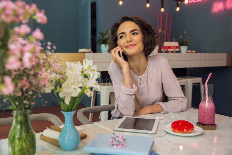 Pretty young woman talking on mobile phone while sitting stock images