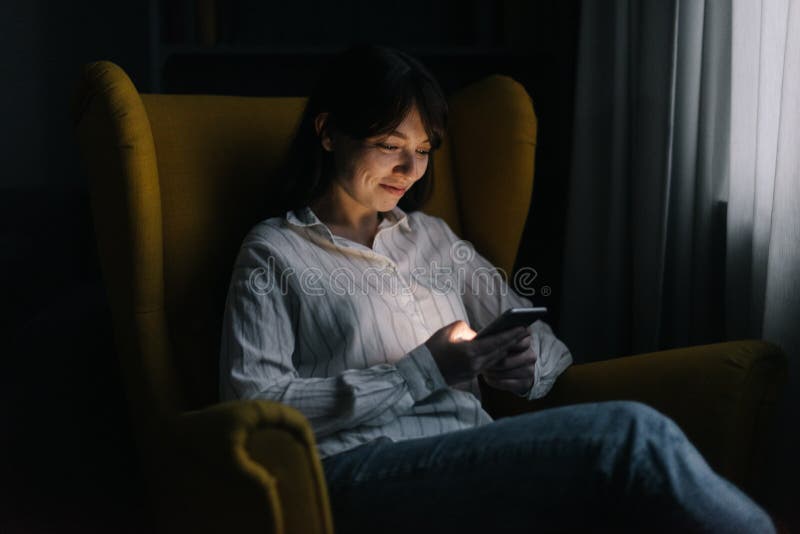Pretty young woman is using phone in dark room. royalty free stock photo Pretty young woman is using phone in dark room. royalty free stock photo