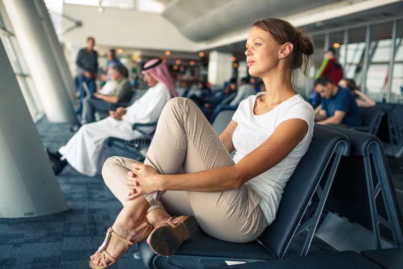 Pretty, young woman waiting at a gate area of a modern airport stock photos.