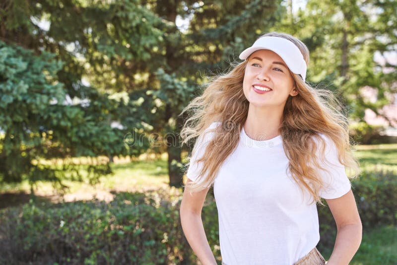 Pretty young woman wearing tennis hat. White t-shirt. Female sport player