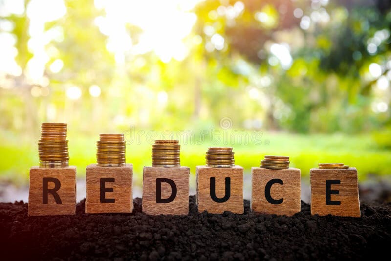 Price reduction, depreciation and devaluation concept. Decreasimg stack of coins on wooden blocks at sunset on natural background.