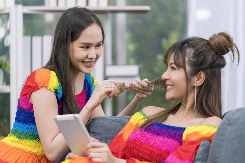 Pride Month. Young woman with tablet sitting on sofa in living room. Woman combing her hair on the sofa stock image