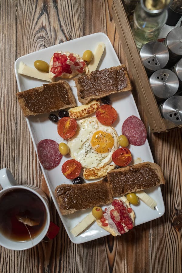 Prima colazione con l'uovo fritto, il pane di segale, il melograno, la pasta della carruba, i formaggi, le olive, il salame asciu fotografie stock libere da diritti Prima colazione con l'uovo fritto, il pane di segale, il melograno, la pasta della carruba, i formaggi, le olive, il salame asciu fotografie stock libere da diritti