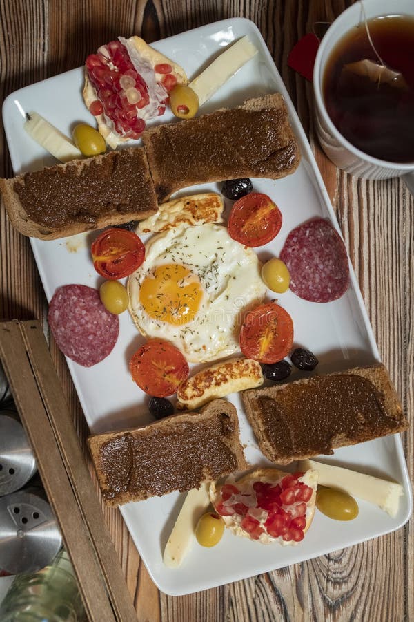 Prima colazione con l'uovo fritto, il pane di segale, il melograno, la pasta della carruba, i formaggi, le olive, il salame asciu immagini stock libere da diritti Prima colazione con l'uovo fritto, il pane di segale, il melograno, la pasta della carruba, i formaggi, le olive, il salame asciu immagini stock libere da diritti