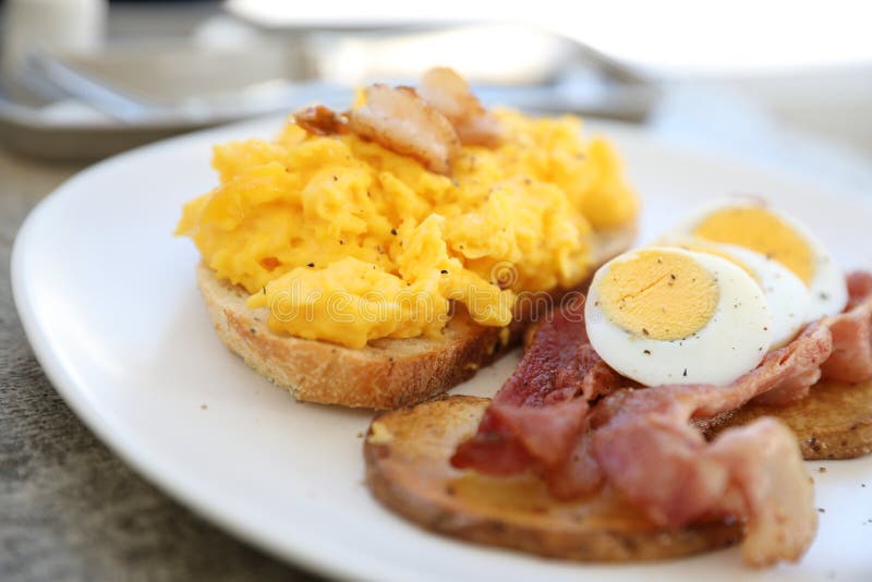 Prima colazione con le uova rimescolate, le patate fritte bacon ed il gamberetto immagine stock Prima colazione con le uova rimescolate, le patate fritte bacon ed il gamberetto immagine stock