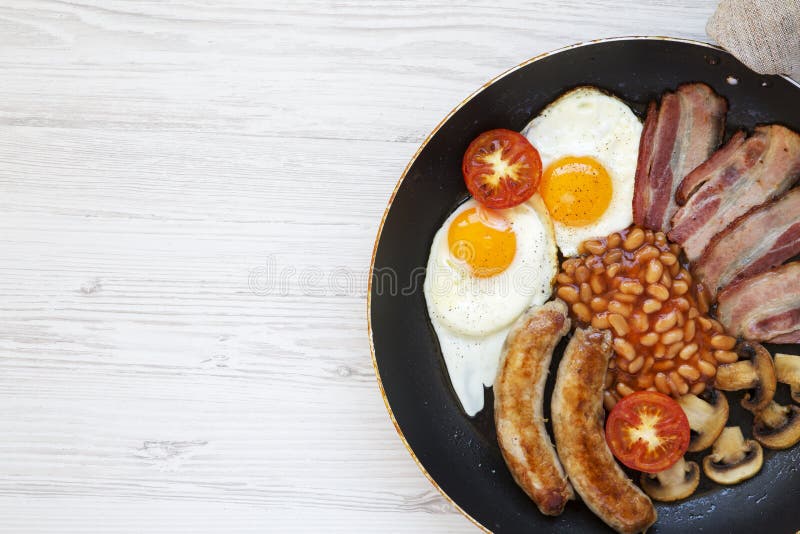 Prima colazione inglese piena nella cottura della pentola con le salsiccie, i funghi, le uova fritte, i fagioli, il pomodoro ed i fotografia stock libera da diritti Prima colazione inglese piena nella cottura della pentola con le salsiccie, i funghi, le uova fritte, i fagioli, il pomodoro ed i fotografia stock libera da diritti