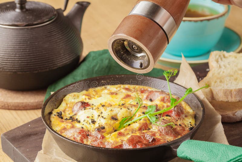 Prima colazione saporita Shakshuka in una pentola del ferro Uova fritte con i pomodori, la cipolla, il prezzemolo, il pane e le e fotografia stock libera da diritti Prima colazione saporita Shakshuka in una pentola del ferro Uova fritte con i pomodori, la cipolla, il prezzemolo, il pane e le e fotografia stock libera da diritti