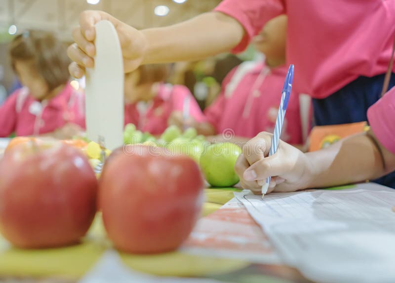 Primary school girls learn and take notes about different types of fruits.