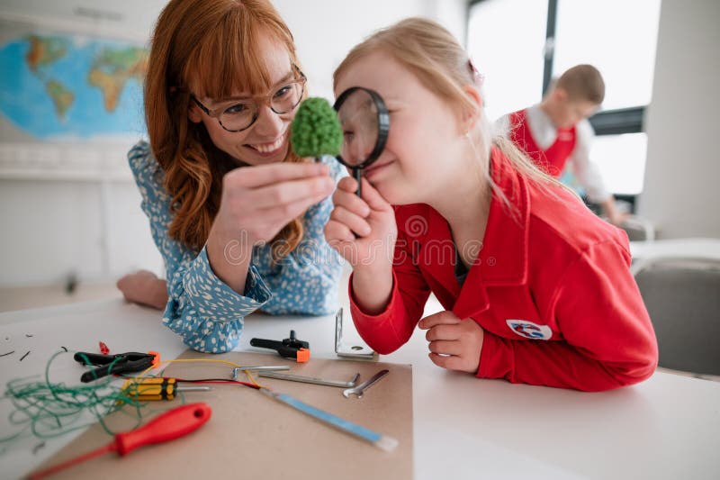 Primary school student with Down syndrome with tutor teacher programming electric toys and robots at robotics classroom