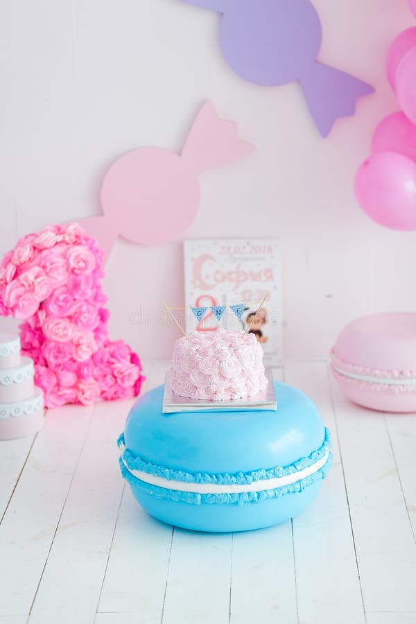 Primer choque del cumpleaños la torta Una torta rosada se coloca en macarrones azules grandes Primer cumpleaños fotos de archivo libres de regalías Primer choque del cumpleaños la torta Una torta rosada se coloca en macarrones azules grandes Primer cumpleaños fotos de archivo libres de regalías