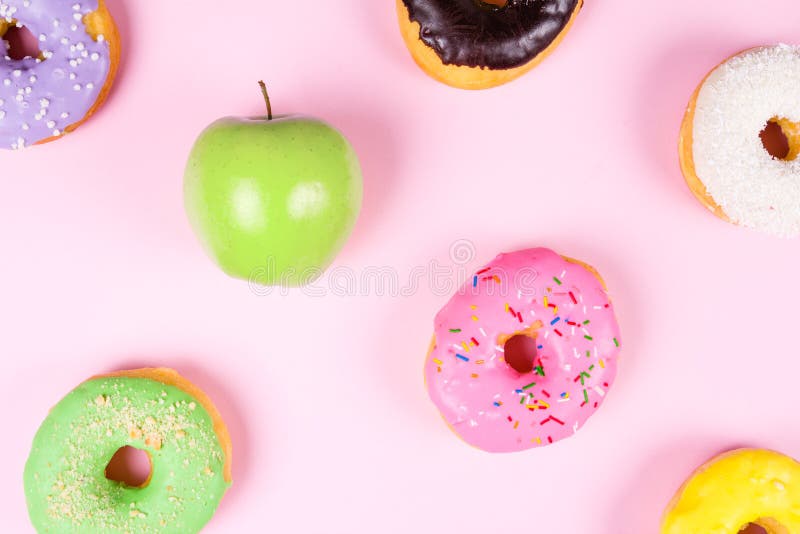Primer de anillos de espuma sabrosos y de la manzana verde fresca en el fondo rosado que sugiere concepto sano de la comida imagen de archivo libre de regalías Primer de anillos de espuma sabrosos y de la manzana verde fresca en el fondo rosado que sugiere concepto sano de la comida imagen de archivo libre de regalías