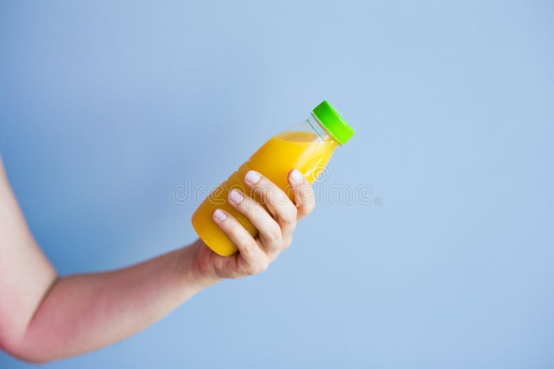 Primer de la mano femenina que sostiene una botella con el jugo imagen de archivo libre de regalías Primer de la mano femenina que sostiene una botella con el jugo imagen de archivo libre de regalías