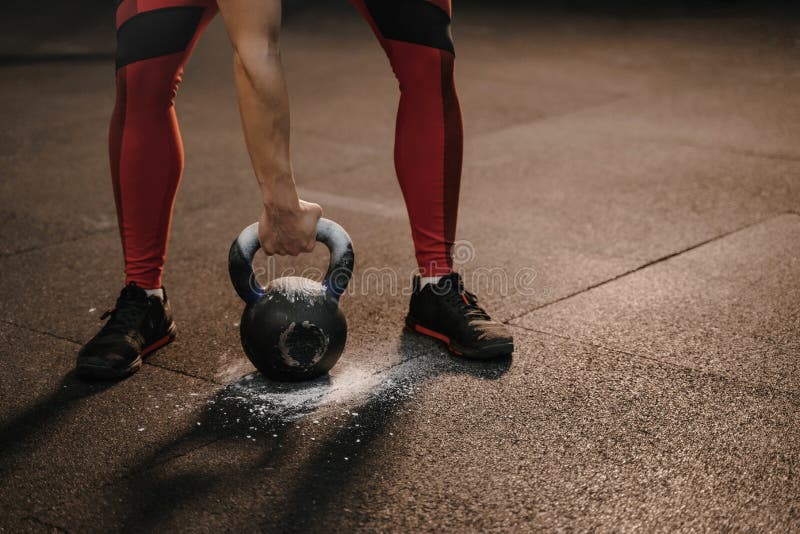 Primer de la mujer de los deportes que lleva a cabo el kettlebell mientras que entrenamiento del crossfit Pesos pesados de elevac foto de archivo Primer de la mujer de los deportes que lleva a cabo el kettlebell mientras que entrenamiento del crossfit Pesos pesados de elevac foto de archivo