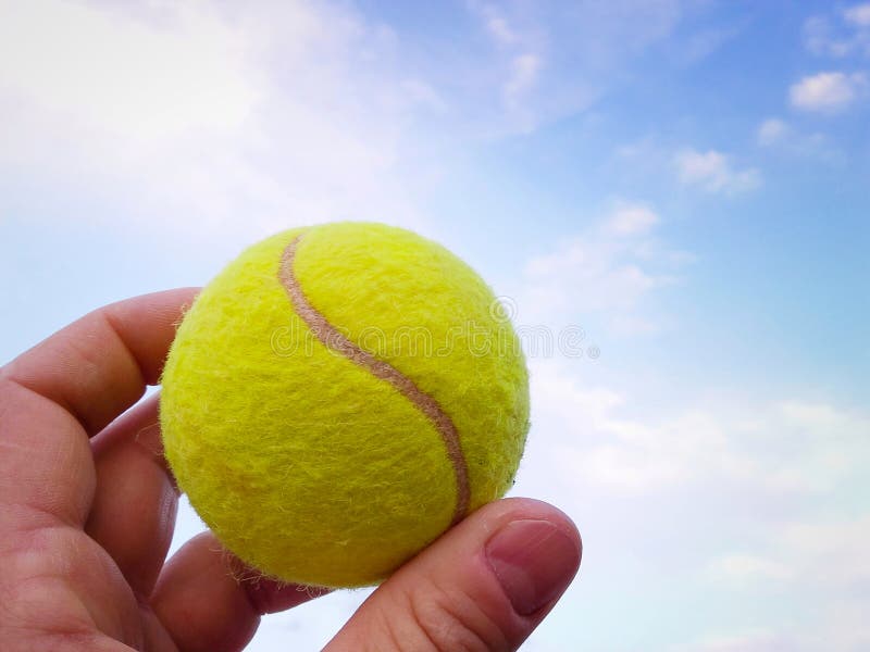 Primer de la pelota de tenis en un cielo azul de los agains de la mano del hombre imagenes de archivo Primer de la pelota de tenis en un cielo azul de los agains de la mano del hombre imagenes de archivo