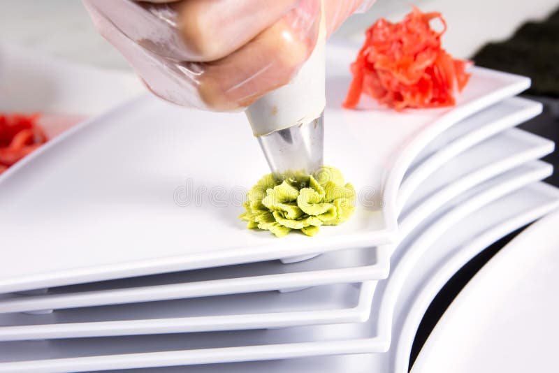 Primer de las manos del cocinero que ruedan encima del ajuste del sushi en la placa en cocina fotografía de archivo libre de regalías Primer de las manos del cocinero que ruedan encima del ajuste del sushi en la placa en cocina fotografía de archivo libre de regalías
