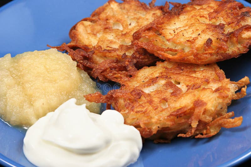 Delicious potato latkes for Hanukah, served on a plate with sour cream and applesauce. Delicious potato latkes for Hanukah, served on a plate with sour cream and applesauce.