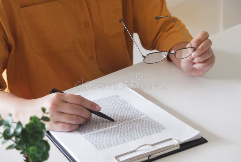 Primer de manos femeninas escribiendo algo y sostener los vidrios en su oficina foto de archivo libre de regalías Primer de manos femeninas escribiendo algo y sostener los vidrios en su oficina foto de archivo libre de regalías