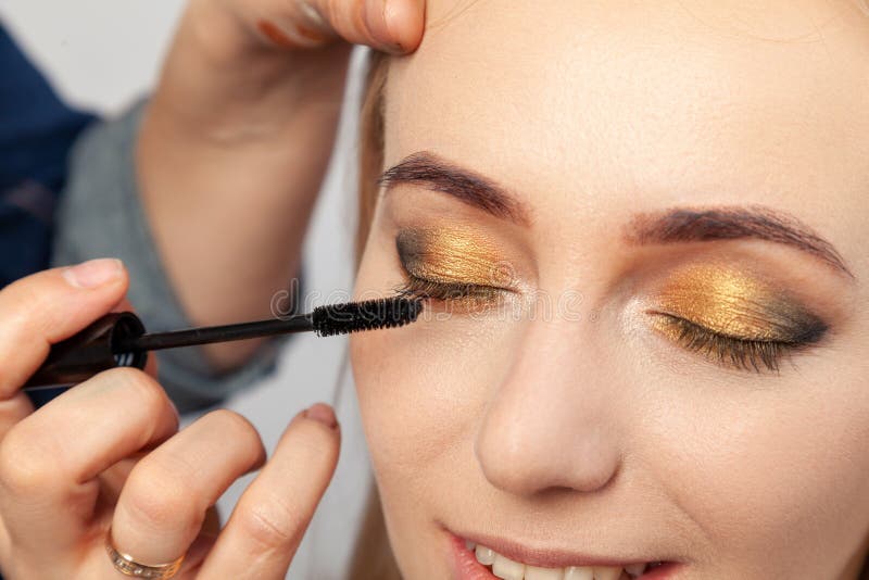 Primer de un maquillaje del ojo del oriental-estilo: las sombras de ojos pronunciadas de oro, marrones y verdes, el artista de ma imagen de archivo Primer de un maquillaje del ojo del oriental-estilo: las sombras de ojos pronunciadas de oro, marrones y verdes, el artista de ma imagen de archivo