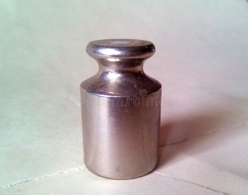 Primer de un pequeño peso del metal para las escalas Metal plateado ligero en un fondo ligero imagen de archivo Primer de un pequeño peso del metal para las escalas Metal plateado ligero en un fondo ligero imagen de archivo