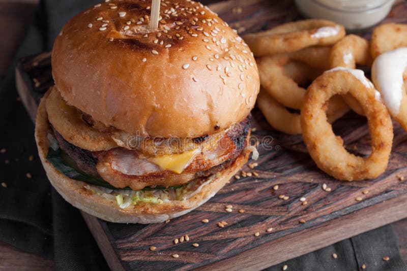Primer de una hamburguesa sabrosa con los aperitivos tales como anillos de cebolla fritos con una salsa de ajo blanca Hamburguesa fotografía de archivo libre de regalías Primer de una hamburguesa sabrosa con los aperitivos tales como anillos de cebolla fritos con una salsa de ajo blanca Hamburguesa fotografía de archivo libre de regalías