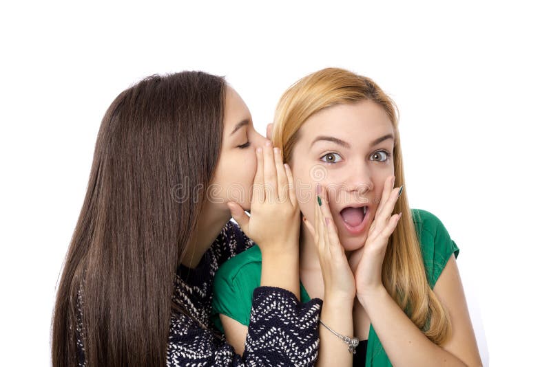 Primer del susurro feliz de dos amigos de chica joven imagen de archivo libre de regalías Primer del susurro feliz de dos amigos de chica joven imagen de archivo libre de regalías