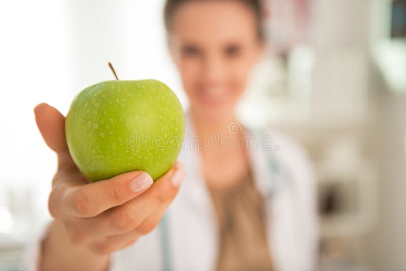 Primer en la mujer del médico que da la manzana imagen de archivo Primer en la mujer del médico que da la manzana imagen de archivo