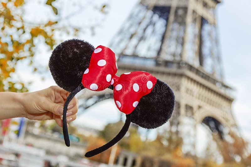 Perfect autumn holidays in Disneyland and Paris. Closeup on Minnie Mouse Ears in female hand on embankment near Eiffel tower in Paris, France. Perfect autumn holidays in Disneyland and Paris. Closeup on Minnie Mouse Ears in female hand on embankment near Eiffel tower in Paris, France