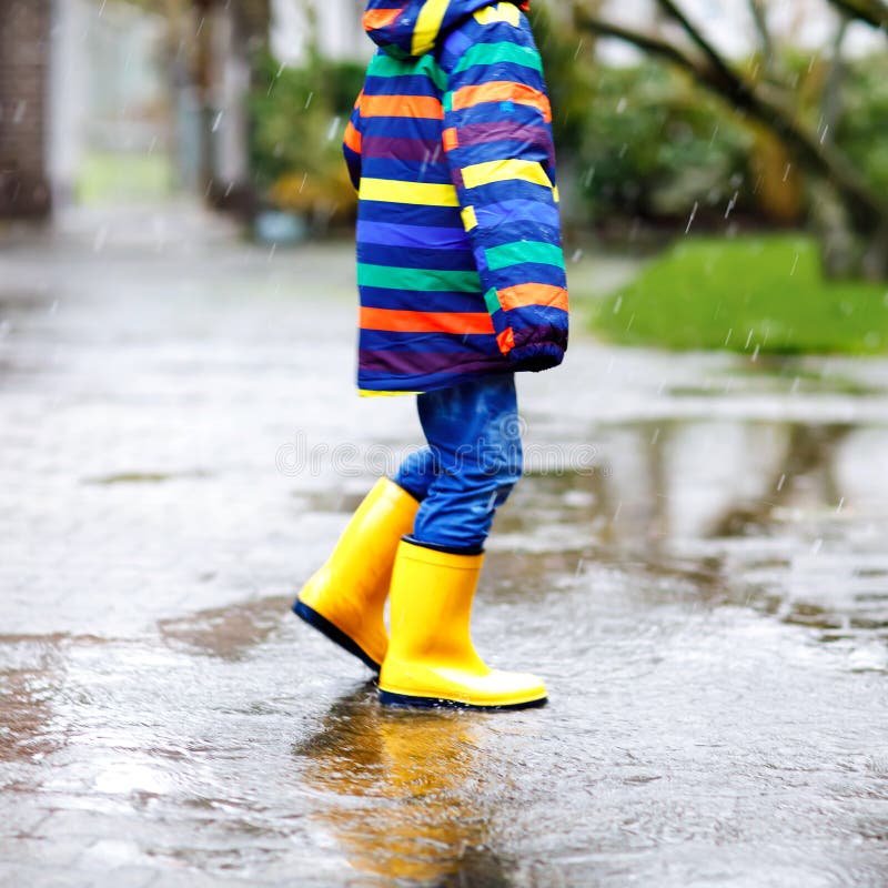 Primer Plano De Un Niño Que Lleva Botas Lluvia Amarillas Durante El Sueño, La Lluvia Y La Nieve En El Día Frío Niño D Foto archivo - Imagen