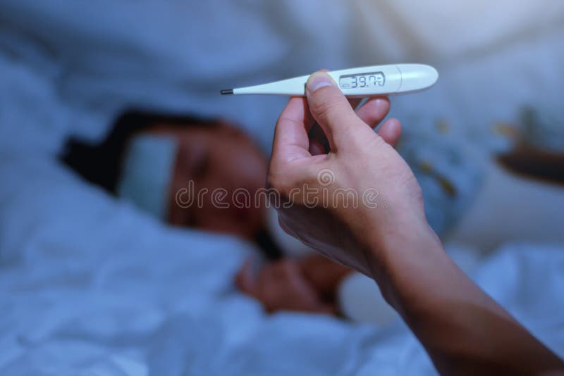 Primero plano del termómetro de la tenencia del padre de la niña enferma en dormitorio en la noche para la alta fiebre del monito imagenes de archivo Primero plano del termómetro de la tenencia del padre de la niña enferma en dormitorio en la noche para la alta fiebre del monito imagenes de archivo