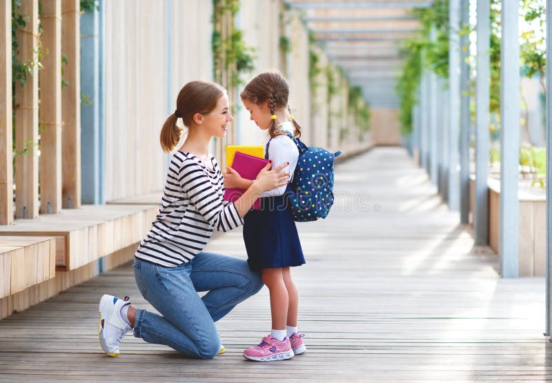 Primo giorno al banco la madre conduce la ragazza della scuola del piccolo bambino nella f fotografie stock libere da diritti