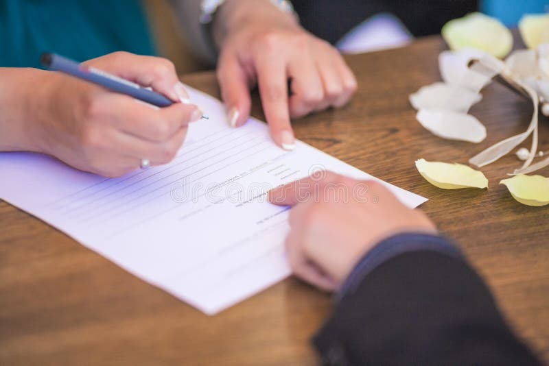 Primo piano del contratto di firma di nozze della mano femminile immagini stock libere da diritti Primo piano del contratto di firma di nozze della mano femminile immagini stock libere da diritti