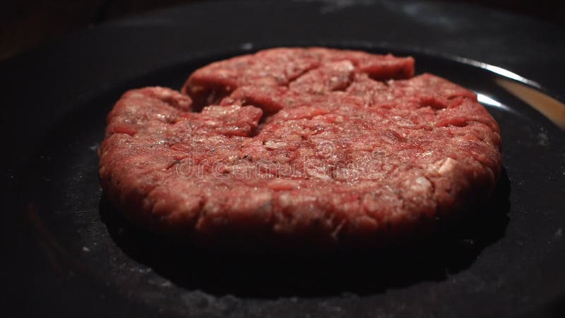 Primo piano del cuoco del cuoco unico che prende una cotoletta dalla pentola nera per la cottura degli hamburger Metraggio di ris immagini stock Primo piano del cuoco del cuoco unico che prende una cotoletta dalla pentola nera per la cottura degli hamburger Metraggio di ris immagini stock