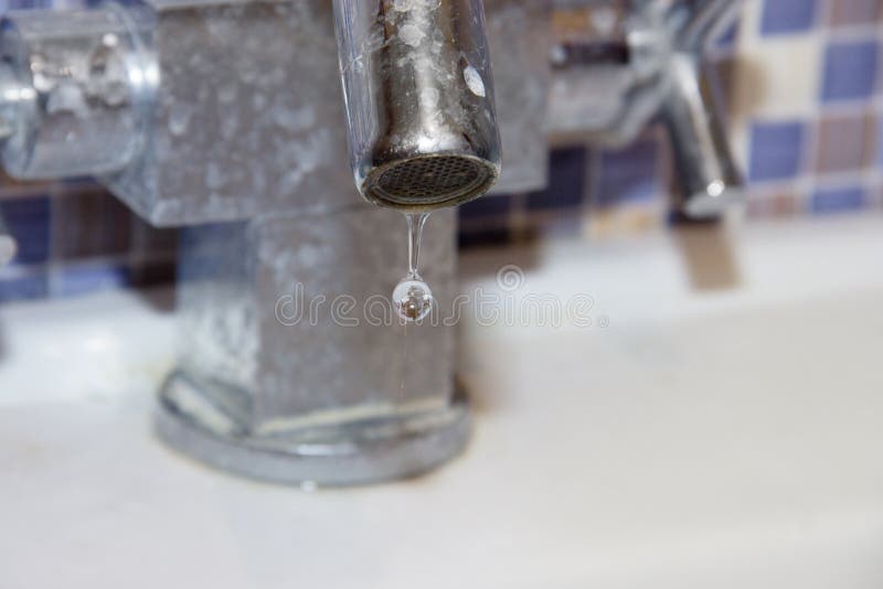 Primo piano del rubinetto di perdita Una goccia enorme dell'acqua cade dal rubinetto coperto di rivestimento calcareo Moto congel fotografia stock Primo piano del rubinetto di perdita Una goccia enorme dell'acqua cade dal rubinetto coperto di rivestimento calcareo Moto congel fotografia stock