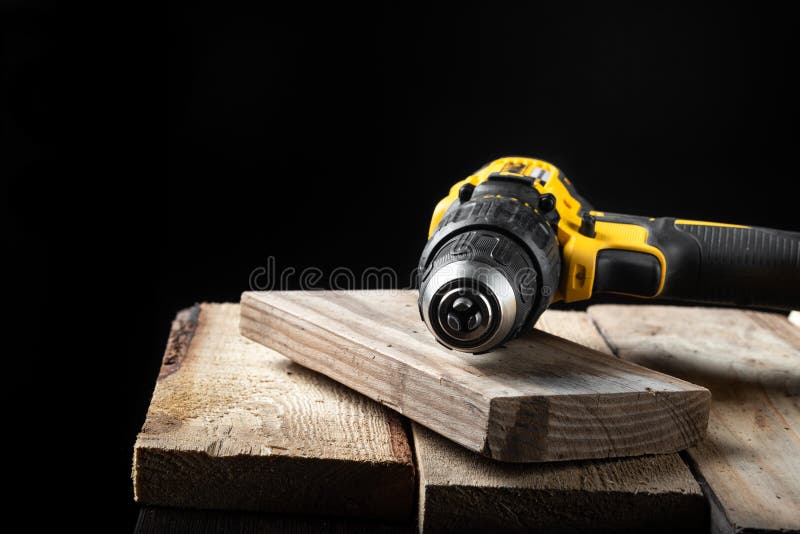 Primo piano del trapano elettrico su un fondo nero con legno ed i trapani Strumenti elettrici Cacciavite della batteria della man fotografie stock libere da diritti Primo piano del trapano elettrico su un fondo nero con legno ed i trapani Strumenti elettrici Cacciavite della batteria della man fotografie stock libere da diritti