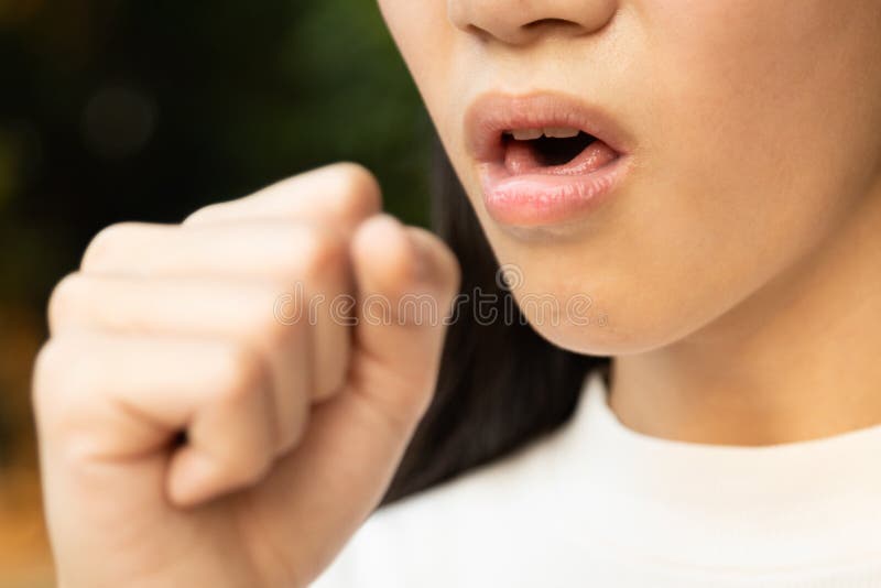 Primo piano della bocca della donna asiatica che tossisce nella mano per prevenire la diffusione della tosse malata della ragazza