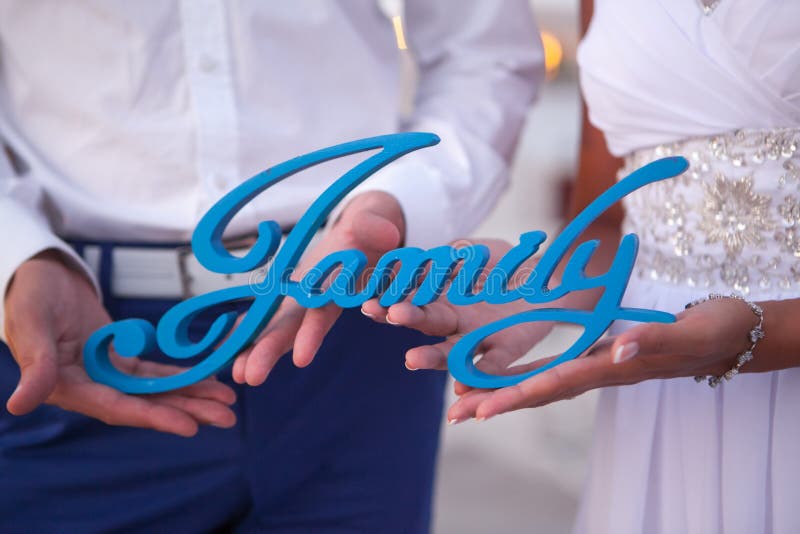 Primo piano della mano di un uomo e di una donna che tengono la famiglia di parole di legno immagini stock Primo piano della mano di un uomo e di una donna che tengono la famiglia di parole di legno immagini stock
