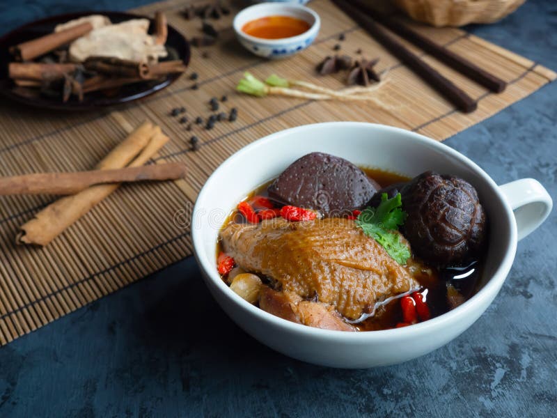 Primo piano della minestra di pollo cinese in una tazza bianca decorata con i funghi di shiitake cinesi, bacche di goji, sangue d fotografia stock Primo piano della minestra di pollo cinese in una tazza bianca decorata con i funghi di shiitake cinesi, bacche di goji, sangue d fotografia stock